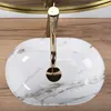 A top-down view of a white marble sink with a gold faucet. Podgląd zdjęcia produktu