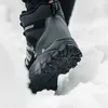 A person's foot wearing a winter boot stepping into snow. Produktbild-Vorschau