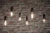 Several Edison-style LED filament light bulbs hang against a brick wall. Produktbild-Vorschau