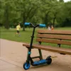 A scooter is parked next to a park bench, with children playing in the background. Anteprima dell’immagine prodotto