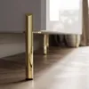A close-up shot of the bottom part of a TV cabinet, focusing on its golden legs and the wooden floor. Náhled obrázku produktu