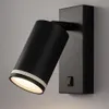 A black wall-mounted spotlight with a white stripe detail, angled to show its light. Náhľad obrázku produktu