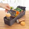 A hand is shown placing a spice packet into a gray plastic organizer filled with various spice packets and two spice jars. Náhled obrázku produktu