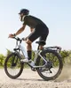 A person riding an e-bike on a dirt path with vegetation in the background. Produktbild-Vorschau