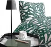A close-up view of a bedding set with a floral pattern, a black lamp, and a tray with a mug and notebook. Produktbild-Vorschau