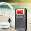 A portable radio and headphones are placed on a wooden surface next to a body of water. Produktbild-Vorschau