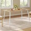 A dining table set up with plates and a cake, in a well-lit room with windows overlooking greenery. Produktbild-Vorschau