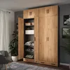 A wardrobe with its doors open, showing shelves with folded clothes, baskets, and boxes. A chair and a plant are visible in the foreground and background. Anteprima dell’immagine prodotto