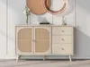A beige sideboard with cane-woven doors and three drawers, displayed in a well-lit room with decorative items on top and a wall with decorative molding behind it. Produktbild-Vorschau