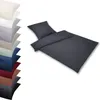 A stack of folded bedding in various colors, with a dark gray duvet and pillow set displayed prominently in the foreground. Produktbild-Vorschau