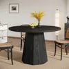 A round black dining table with a fruit bowl and vase of flowers on it, set in a dining room with chairs and a dresser. Produktbild-Vorschau