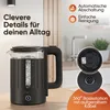 A black glass kettle with water inside, placed on a wooden surface with kitchen background elements. The image includes text overlays highlighting product features. Produktbild-Vorschau