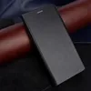 A black flip cover case for a phone is shown on a surface with different textures. Produktbild-Vorschau