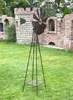 A metal windmill garden stake stands in a grassy yard in front of a brick castle-like structure. Anteprima dell’immagine prodotto