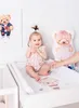 A baby sitting on a changing mat with teddy bear decorations. Produktbild-Vorschau
