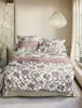 A neatly made bed with a patterned duvet and pillows in a bedroom setting. Produktbild-Vorschau