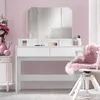 A white vanity table with a tri-fold mirror and pink accents in a room with pink walls. Náhled obrázku produktu