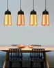 Four pendant lights hang above a wooden dining table with chairs. Produktbild-Vorschau