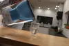 A person is pouring filtered water from a blue and clear pitcher into a clear glass on a wooden counter in a kitchen. Náhľad obrázku produktu
