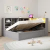 A grey bed with its storage compartment open, revealing the mattress and storage space. The bed is in a child's room with decorations on the wall and toys on the floor. Anteprima dell’immagine prodotto