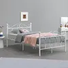 A white metal bed frame with bedding in a room. Podgląd zdjęcia produktu