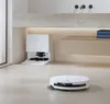 A white robot vacuum cleaner and its charging station are shown on a light-colored floor in a modern bathroom setting. Produktbild-Vorschau
