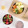 A top-down view of stainless steel food containers filled with food, placed on a wooden cutting board and a white surface. Produktbild-Vorschau