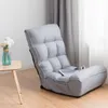 A gray floor chair is shown in a room with a wooden floor and curtains in the background. Produktbild-Vorschau