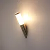 A modern wall lamp with a motion sensor, made of stainless steel, mounted on a light gray wall. Produktbild-Vorschau