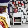 A bedroom scene with a bed, a nightstand, and patterned tiles. Produktbild-Vorschau