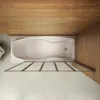 Top-down view of a bathtub with a glass shower screen in a bathroom with wooden and tiled walls. Produktbild-Vorschau