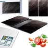 A product shot of glass cutting boards with a slate-like pattern, along with packaging and decorative elements like tomatoes and basil. Voir les images du produit