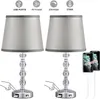 Two identical crystal table lamps with gray fabric shades are shown, with icons and text above indicating features like USB ports, dimmability, and color temperature. Phones are shown charging from the lamps. Produktbild-Vorschau