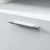 A close-up shot of a modern cabinet handle on a white surface. Produktbild-Vorschau