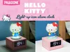 A collage showing a Hello Kitty alarm clock with two different lighting conditions, along with marketing text and branding. Podgląd zdjęcia produktu