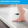 A person's feet are shown standing on a white shower tray with a textured surface and a drain. Anteprima dell’immagine prodotto