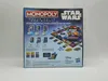 The back of a Hasbro Star Wars Monopoly board game box, showing game components and descriptions. Produktbild-Vorschau