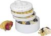 A white food dehydrator with multiple stacked trays filled with dried fruits, next to fresh bananas and apples, and a pile of dried fruit on the side. Anteprima dell’immagine prodotto