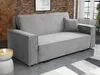 A grey sofa bed is shown in a living room setting with a brick wall and wooden paneling in the background. Náhled obrázku produktu
