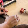 Hands are shown working with brown textured material on a wooden surface, with a staple gun and a roller tool nearby. Produktbild-Vorschau
