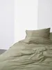 A close-up view of a bed with green bedding, including a duvet and pillow, against a white background with soft vertical shadows. Produktbild-Vorschau