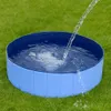 A blue foldable dog pool is being filled with water on a green grassy lawn. Náhled obrázku produktu