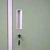 A close-up view of a green metal locker door with a silver handle and a key in the lock. Produktbild-Vorschau
