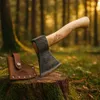 An axe and its leather sheath are placed on a moss-covered tree stump in a forest setting with dappled sunlight. Anteprima dell’immagine prodotto