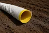 A drainage pipe lying on brown soil. Produktbild-Vorschau