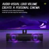 A soundbar is placed in front of a monitor displaying a scene with a car and mountains. The soundbar has purple glowing rings around its speakers. Náhled obrázku produktu