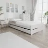 A white bed with a mattress and drawers is shown in a bedroom setting. Náhled obrázku produktu