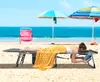 A woman is lying on a massage table on a beach, under umbrellas. Anteprima dell’immagine prodotto