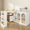 A white bar cabinet with glass doors and open shelving is shown in a living room setting, with a brown leather sofa visible behind it. Produktbild-Vorschau