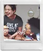 Two young women are sitting on a bed, laughing and eating donuts. Voir les images du produit